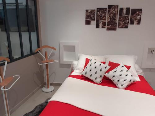 Schlafzimmer mit einem Bett mit roten und weißen Kissen in der Unterkunft chez le tit in Mèze