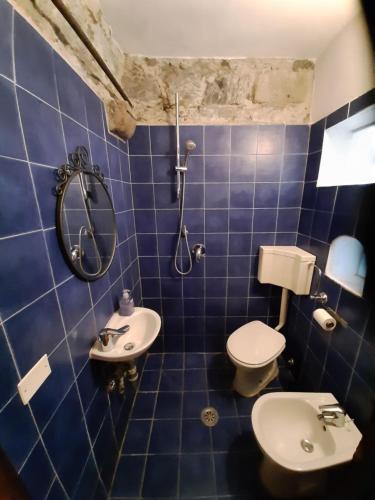 y baño de azulejos azules con aseo y ducha. en Castello di Rometta Private Pool, en Fivizzano
