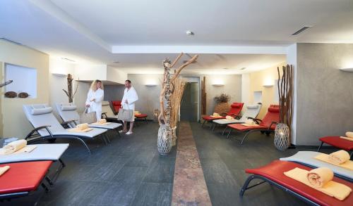 two people standing in a room with tables and chairs at Hotel Residenz Hochalm - Joker Card Partner in Saalbach Hinterglemm