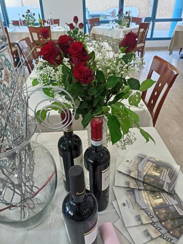 a table with two bottles of wine and red roses at Hotel Ascot Riccione in Riccione
