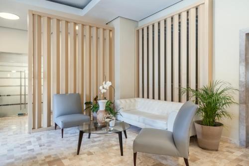 a living room with a white couch and two chairs at JOIA Rose Hall by Iberostar - Adults Only All Inclusive Resort in Montego Bay