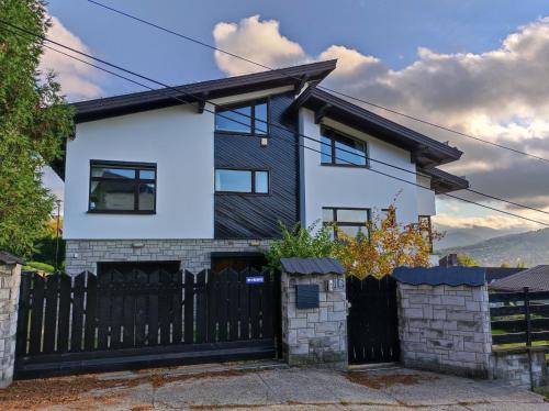 a white and black house with a black fence at Apartamenty Monterska in Bielsko-Biała