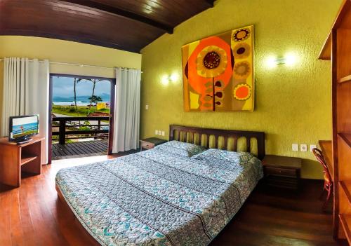 a bedroom with a bed and a television and a window at Hotel Pousada do Sol in Ubatuba