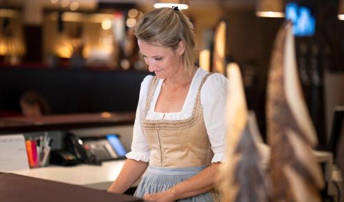 a woman standing at a counter in a restaurant at Hotel Residenz Hochalm - Joker Card Partner in Saalbach Hinterglemm