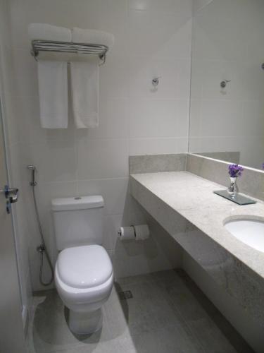 a white bathroom with a toilet and a sink at Samba Tres Rios in Três Rios