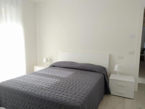 1 dormitorio blanco con 1 cama y 2 mesitas de noche en Jesolo Appartamenti F2 - Ocean Blue en Lido di Jesolo