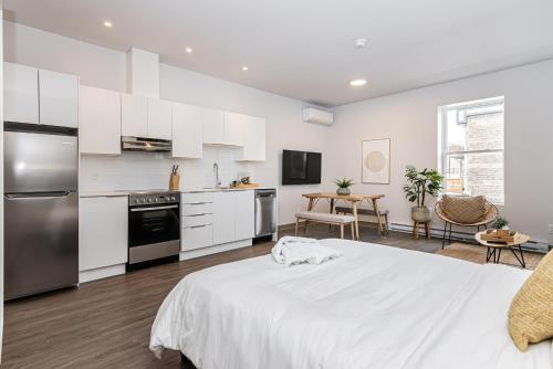 a white kitchen with a large bed in a room at Brand New and Perfectly Located Flat in Le Plateau by Den Stays in Montréal