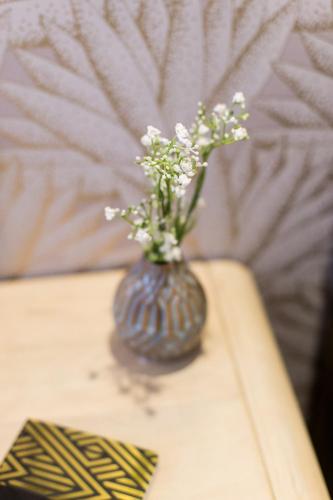 a vase with flowers in it sitting on a table at Serene and Styled Little Italy Studio full bath by Den Stays in Montréal