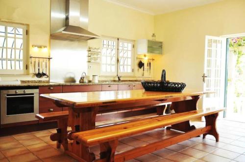 a kitchen with a wooden table and a bench at Fabulosa Quinta do Vento in Palmela