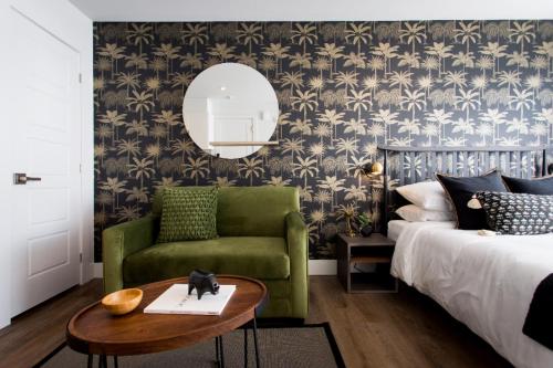 1 dormitorio con cama, silla verde y espejo en Golden Oasis Studio with Yard View and full bath by Den Stays, en Montreal