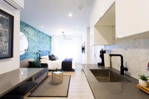 a kitchen with a sink and a living room at Studio Palms Steps from JeanTalon Market Full Bath by Den Stays in Montréal
