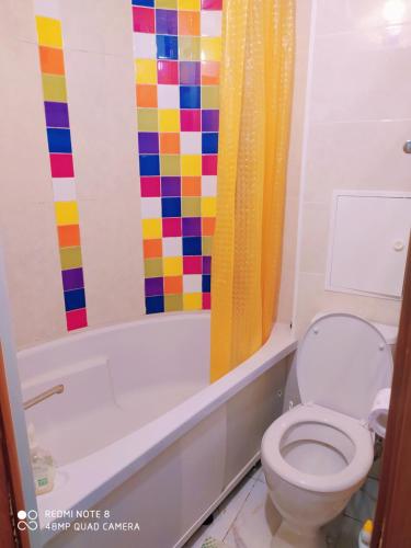 a bathroom with a toilet and a colorful shower curtain at Апартаменты на Пушкина, 13 in Perm