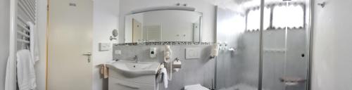 ein weißes Badezimmer mit einem Waschbecken und einem Spiegel in der Unterkunft Bad Pyrmonter Hof in Bad Pyrmont