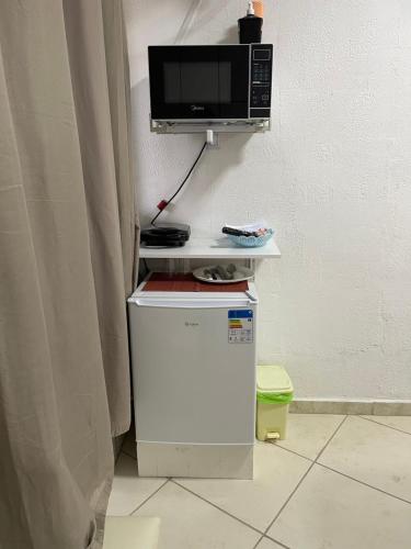 a microwave sitting on top of a refrigerator at BERTIOGA PRAIA suítes in Bertioga