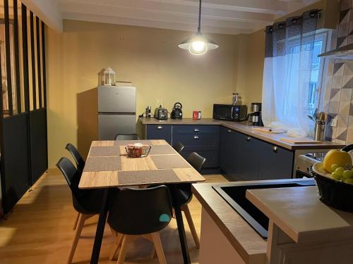 une cuisine avec une table, des chaises et un réfrigérateur dans l'établissement Le Maine N 5 - FLÉAC ANGOULEME - Suite Harry Potter, à Fléac