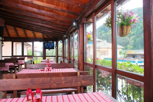 a restaurant with wooden tables and chairs and windows at Family Hotel Flora in Zlatograd