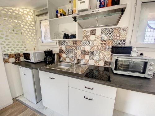 une cuisine avec un évier et un micro-ondes dans l'établissement St Louis Studio mansardé atypique climatisé, à Sète