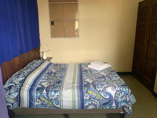 a bedroom with a bed with a blue and white comforter at Kasa Kiwi Hostel & Travel Agency in Quetzaltenango