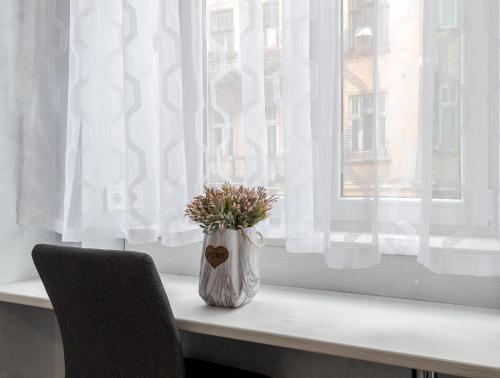 un jarrón con flores sentado en el alféizar de la ventana en Golden Violin ! Apartments Lviv S, en Leópolis
