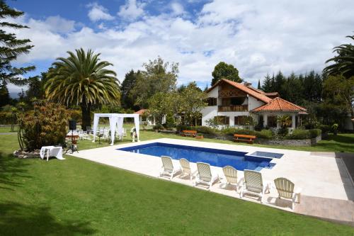 un patio trasero con piscina, sillas y una casa en Quinta La Constanza, en Tababela