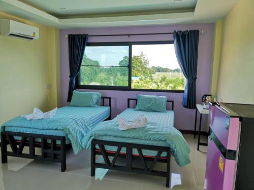 a bedroom with two twin beds and a window at BN Resort in Ban Nong Chum Saeng