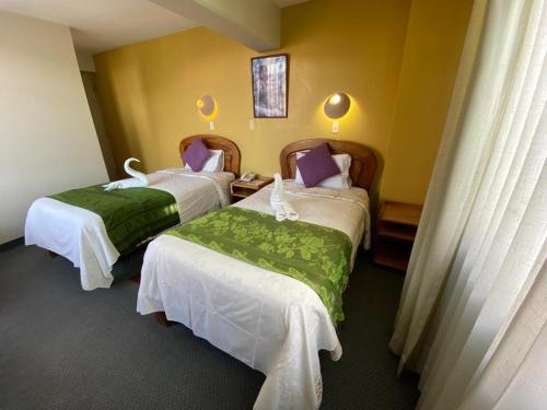 a hotel room with two beds with white and green sheets at Hostal Oscar Inn in Puno