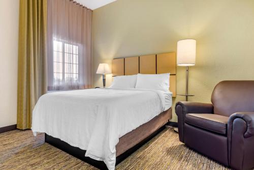 a hotel room with a bed and a chair at Candlewood Suites Alabaster by IHG in Alabaster