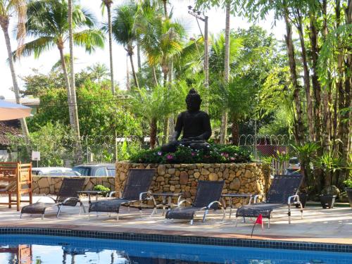a statue in front of a pool with chairs and a statue at Ilha Flat Hotel Suíte Bella - 4207 - Ilhabela in Ilhabela