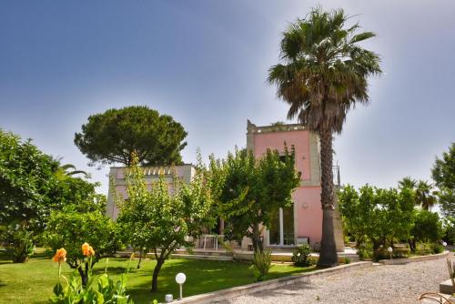 a pink building with a palm tree in a park at Villa Sirgole Rosa with Pool, Galatina in Cutrofiano