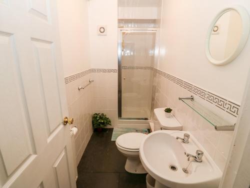 a white bathroom with a toilet and a sink at Avondale in Porthmadog