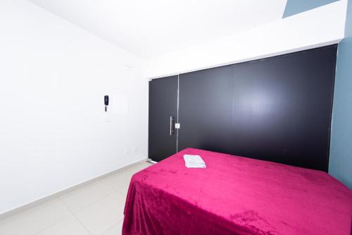 a room with a pink bed with a black wall at Jahu Center Plaza Flats in Jaú