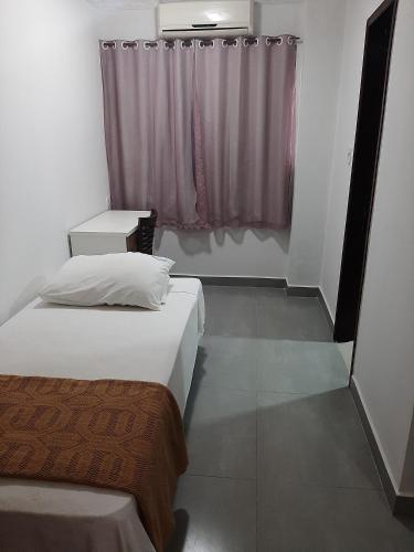 two beds in a small room with a window at PEDRA BONITA PRECIOSO HOTEL ltda in Itaboraí