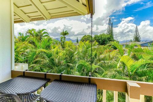 a balcony with two chairs and a view of palm trees at Paniolo #202B in Princeville