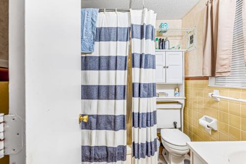 a bathroom with a striped shower curtain and a toilet at Seaward Villas 5 in Myrtle Beach