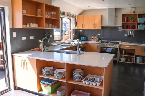 a kitchen with a sink, stove, dishwasher and cabinets at Adventure Queenstown Hostel in Queenstown