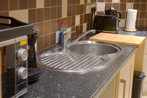a kitchen counter with a sink and a microwave at Stunning Holiday Home Woodcote View in Oakworth