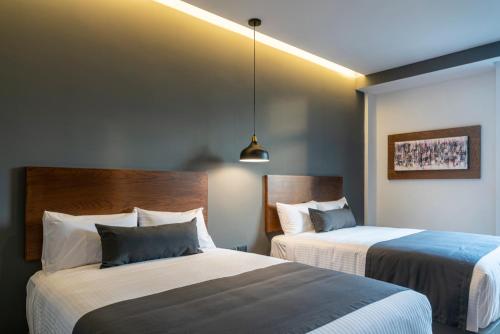 ein Hotelzimmer mit zwei Betten in einem Zimmer in der Unterkunft Gumont Guadalajara López Mateos - Minerva in Guadalajara