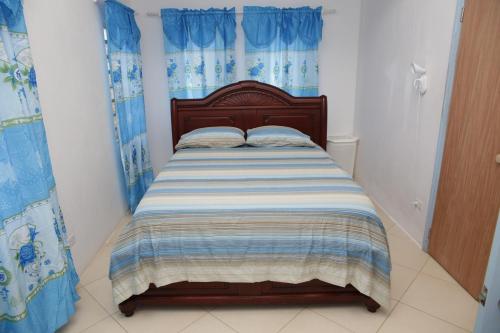 a small bedroom with a bed with blue curtains at Breezee in Long Path