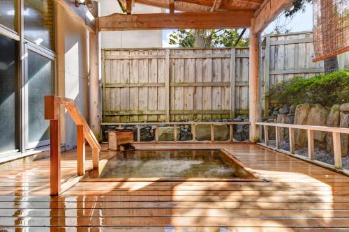 a hot tub on a deck with a wooden fence at Yanagi No Yu in Aomori