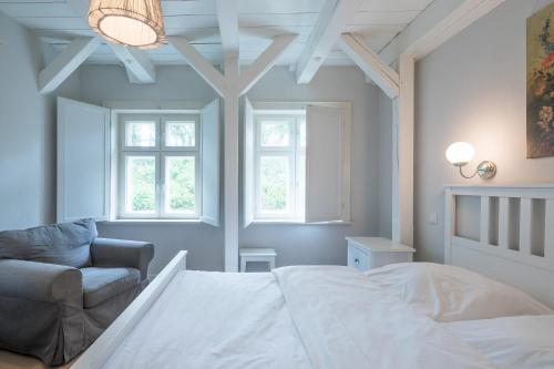 a bedroom with a bed and a chair and windows at Ferienhaus Achter de Diek in Altneukoogsbühr