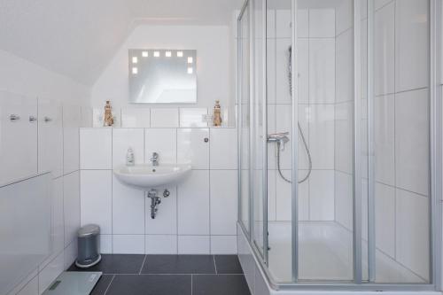 a white bathroom with a shower and a sink at DeKo in Husum