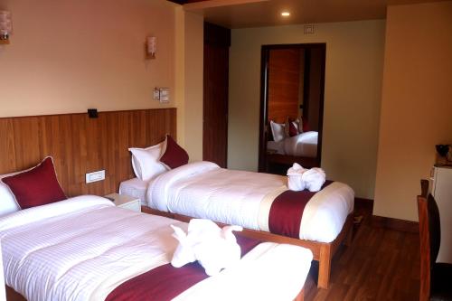 a hotel room with three beds with white sheets at Hotel Family Ties Pvt. Ltd. in Kathmandu
