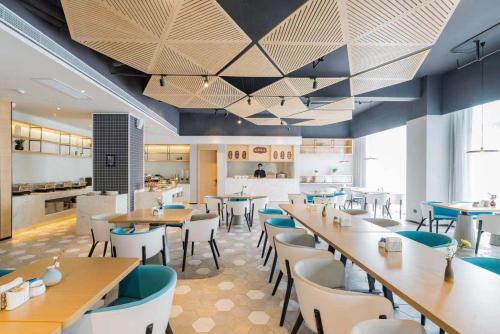 Atour Hotel Hangzhou Future Technology City Haichuang Park في هانغتشو: مطعم بطاولات وكراسي ومطبخ