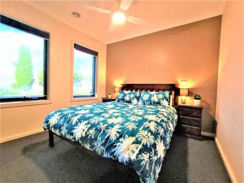 a bedroom with a bed with a blue bedspread and two windows at My Place in Albury in Albury