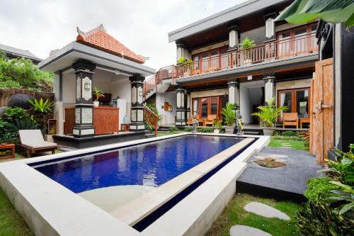 a villa with a swimming pool in front of a house at Prama Beach Canggu by The Loka in Canggu