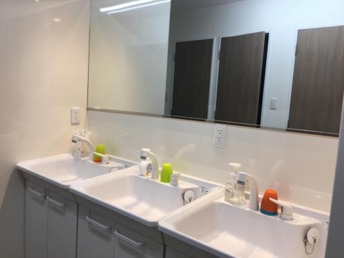 baño con 2 lavabos y espejo grande en Family Hostel Umeda near One floor 110 m² Private spac, en Osaka