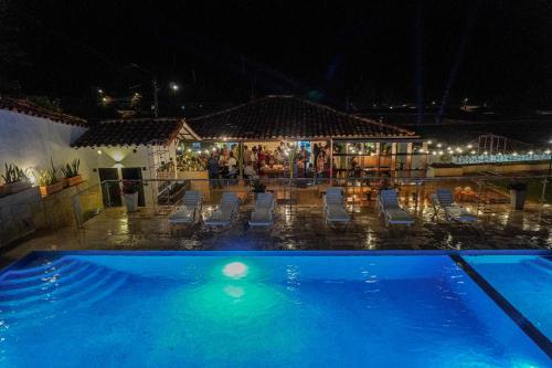a swimming pool with chairs and a bar at night at Don Juan De Dios De Guane Hotel & Centro De Convenciones in Barichara