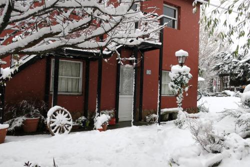 a red house with snow on the branches of a tree at Hospedaje Mi Rincón El Chaltén in El Chalten