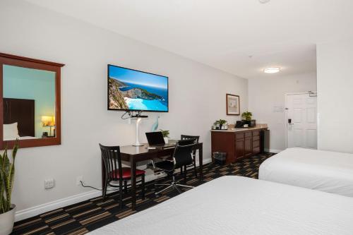 a hotel room with a desk and a bed and a bedroom at The Hotel Oceanside in Oceanside
