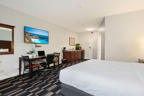a hotel room with a bed and a desk with a computer at The Hotel Oceanside in Oceanside